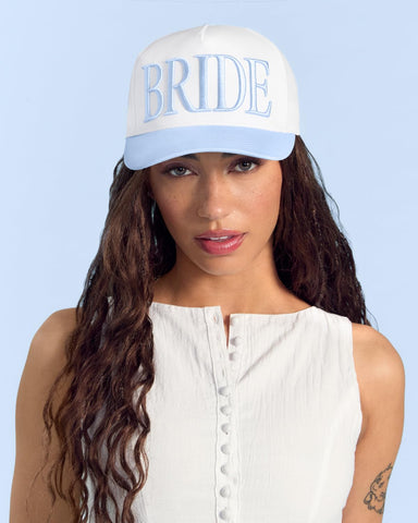 xo Fetti blue embroidery on white hat adds bridal flair.