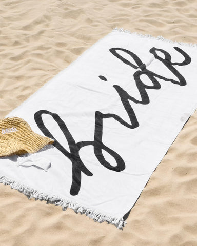 xo Fetti Bride Fringe Beach Towel laid flat with 30x67 inches length for lounging.
